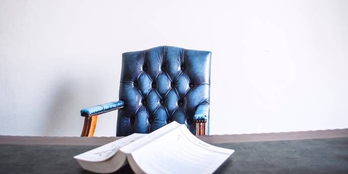 Blue chair sitting behind a desk with a book lying face down on the table